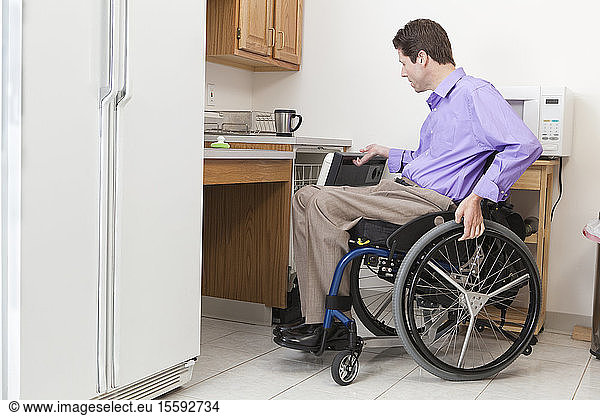 Man in wheelchair with spinal cord injury opening accessible dishwasher