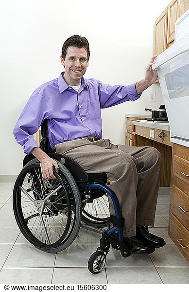 Man in wheelchair with spinal cord injury opening oven in an accessible kitchen