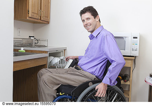 Man in wheelchair with spinal cord injury putting dishes in an accessible dishwasher