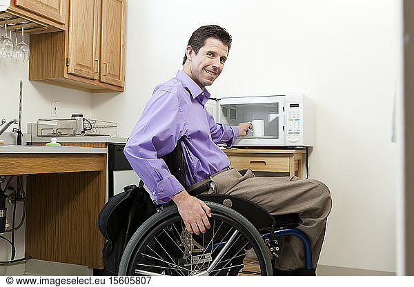 Man in wheelchair with spinal cord injury removing cup from an accessible microwave