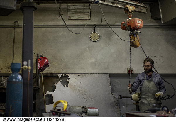 Man in workshop using chain hoist
