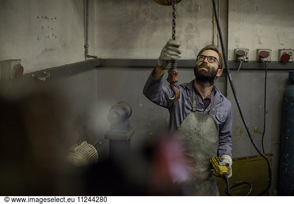 Man in workshop using chain hoist