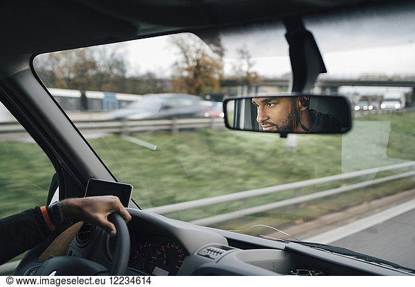 Man is reflecting on rear-view mirror of delivery van