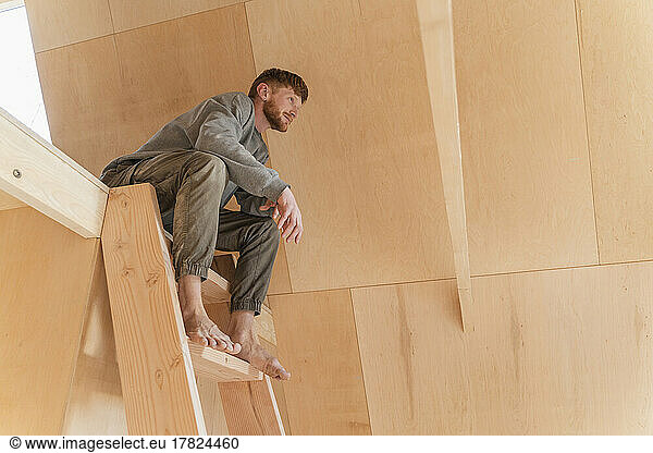 Man is sitiing on the second floor ladder in eco house