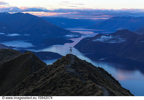 Man jumping in air at the top of mountain during blue hour.