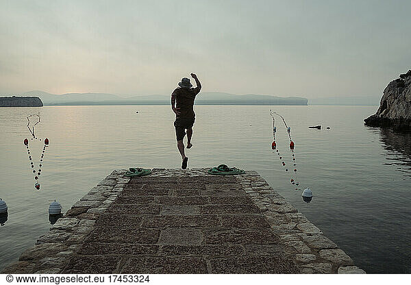 Man jumps from a jetty into the water.