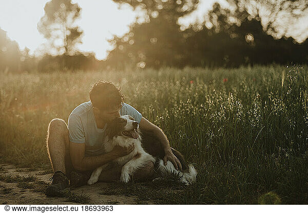 Man kissing border collie dog at field