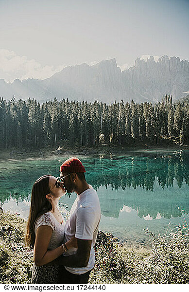 Man kissing girlfriend near Carezza lake in South Tyrol  Italy