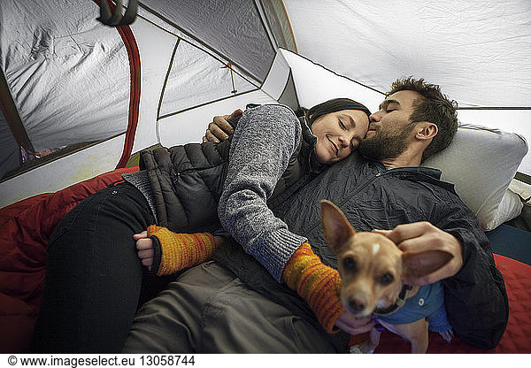 Man kissing girlfriend on forehead while relaxing in tent