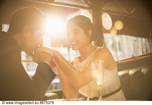 Man kissing girlfriend's hand in restaurant