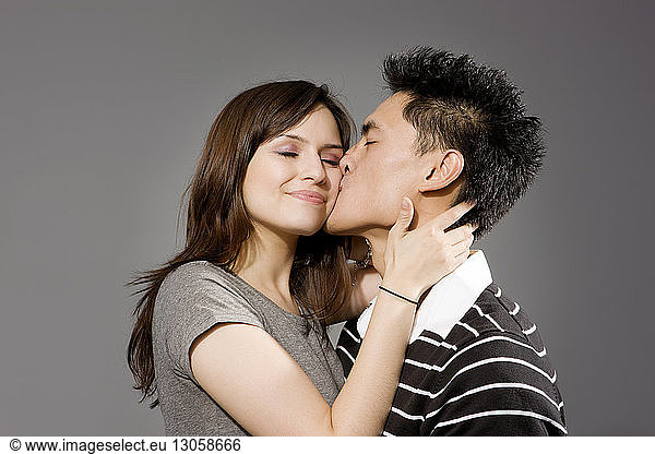 Man kissing woman against gray background