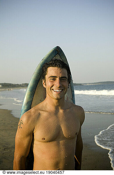 Man leaning against surfboard  Scarborough Beach  Maine  New England.