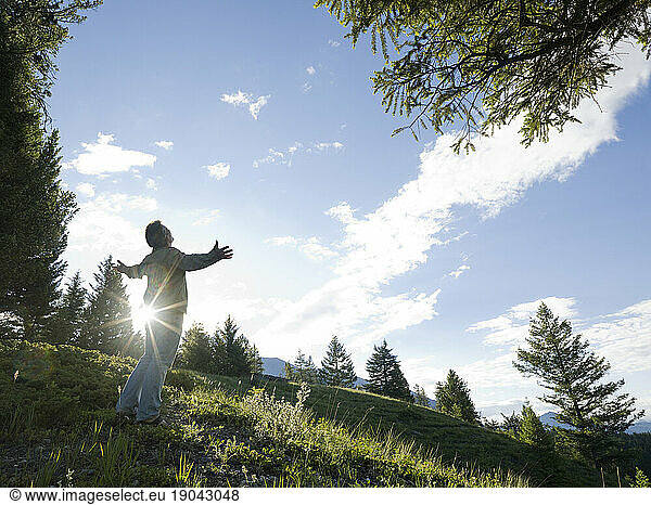 Man leans against tree and looks over forest