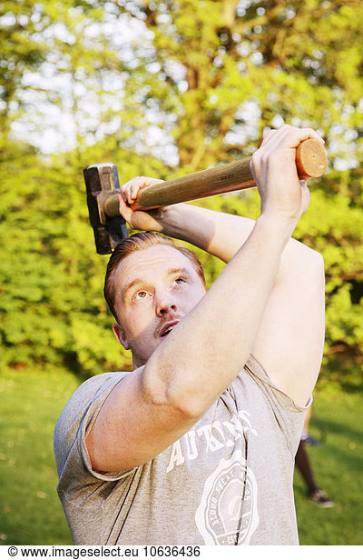 Man lifting hammer in park