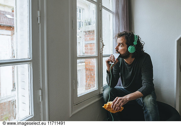 Man listening music with headphones and smartphone at home