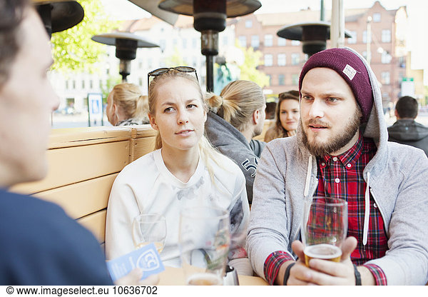 Man looking at friend while holding beer glass