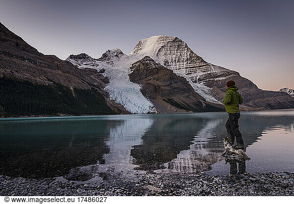 Man looking at Mount Robson above Berg lake at dawn.