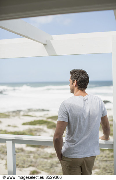 Man looking at ocean view from balcony
