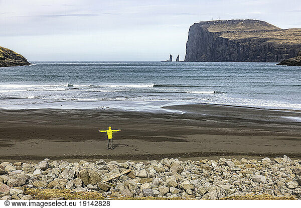Man looking at sea stacke Risin and Kellingin standing on beach