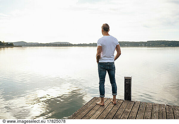 Man looking at view from pier over lake