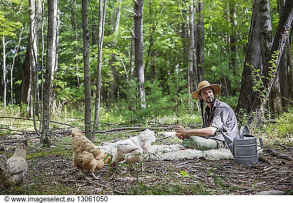 Man looking away while sitting on blanket in forest
