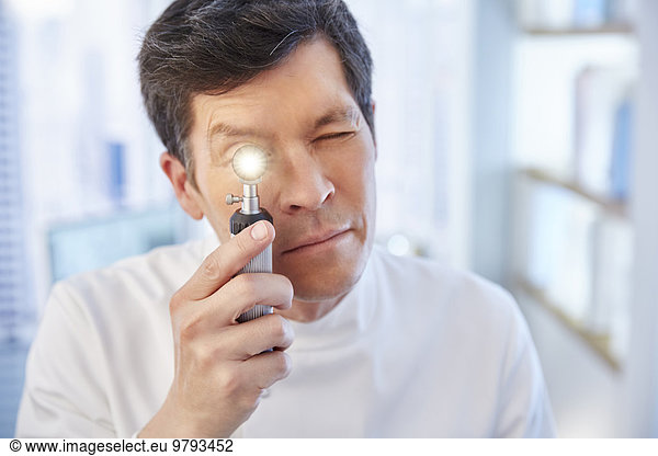 Man looking through illuminated speculum in laboratory