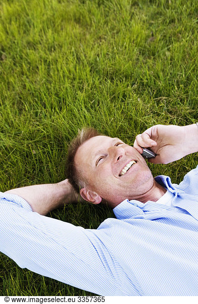 Man lying in the grass talking in cellphone