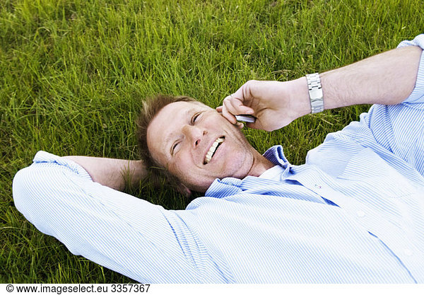Man lying in the grass with cellphone