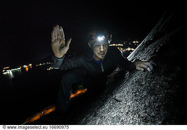 Man making funny face and high five after topping out night climbing