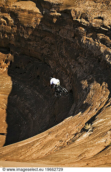 Man mountain biking down steep rock in Moab  Utah.