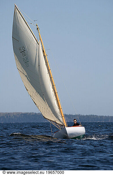 Man navigates waters of Penobscot Bay off the coast of Maine in daysailer.