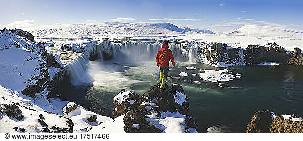 man observe frozen waterfall from aerial view named Godafoss