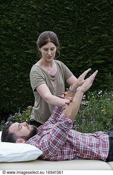 Man on a couch and therapist raising his arms in a garden therapy session