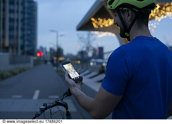 Man on bicycle video chatting with smart phone in city at night