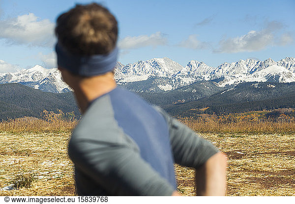 Man on trail run looks at Gore Range mountains from Vail  Colorado