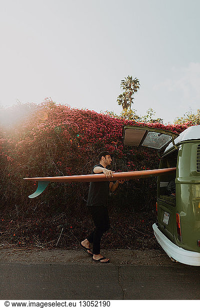 Man on van road trip loading surfboard  Ventura  California  US