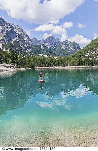 Man paddleboarding on turquoise Pragser Wildsee against mountain range  Dolomites  Alto Adige  Italy
