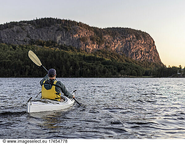 Man paddles in Kayak across Moosehead Lake towards Mount Kineo  Maine