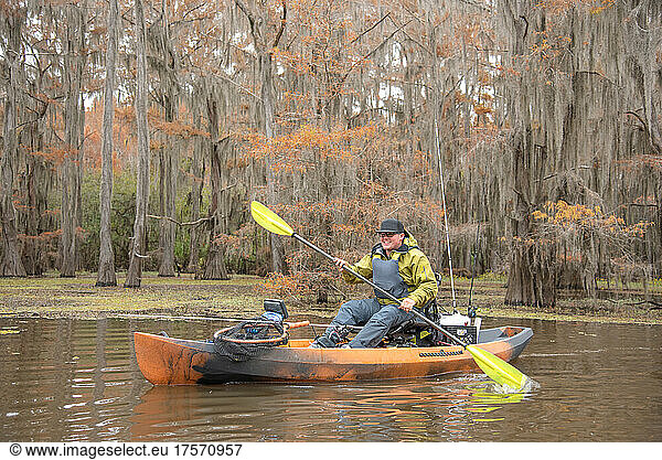 man paddling in cypress forest
