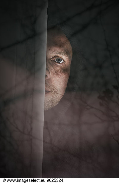 Man peeking from behind windowpane