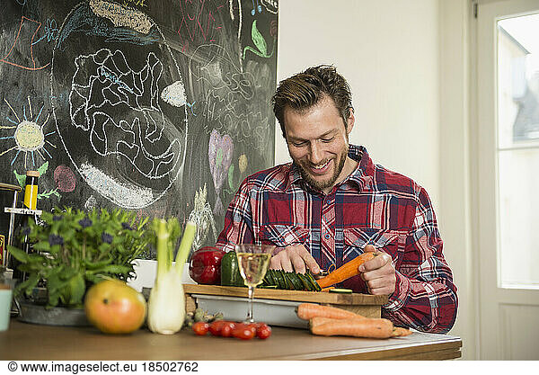Man peeling carrot on chopping board  Munich  Bavaria  Germany