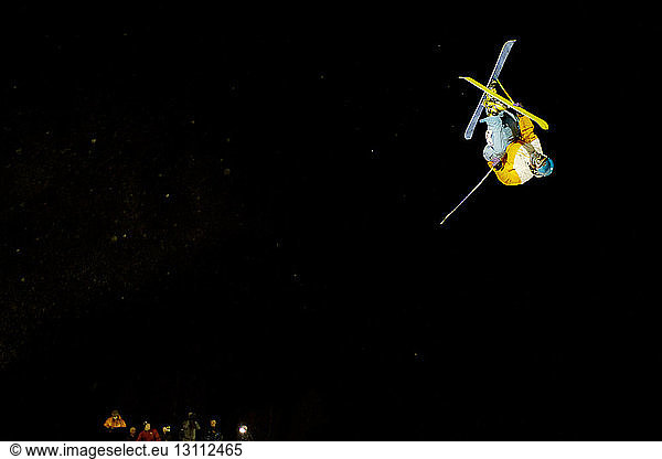 Man performing freestyle skiing jump at night