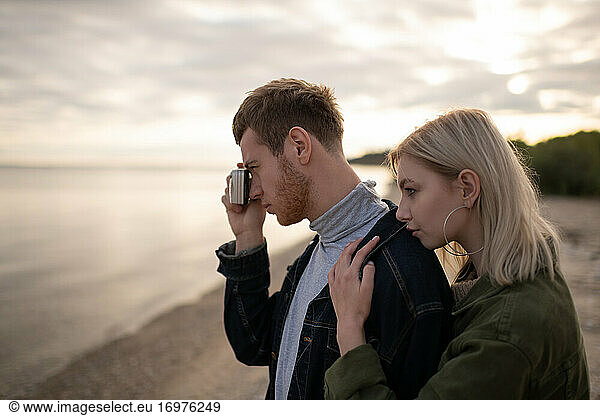 Man photographer with girlfriend on lake coast