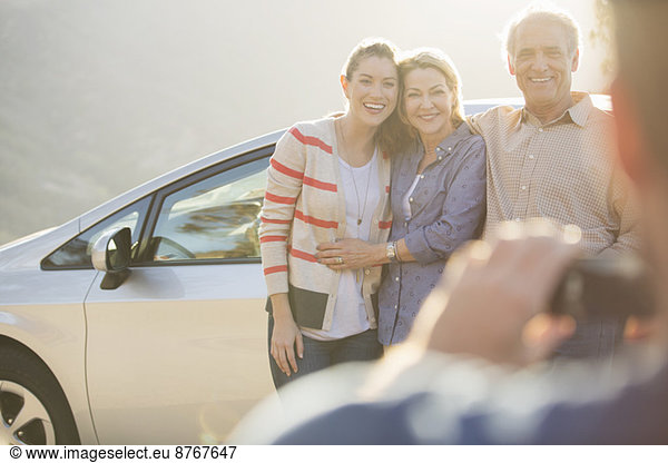 Man photographing family outside car