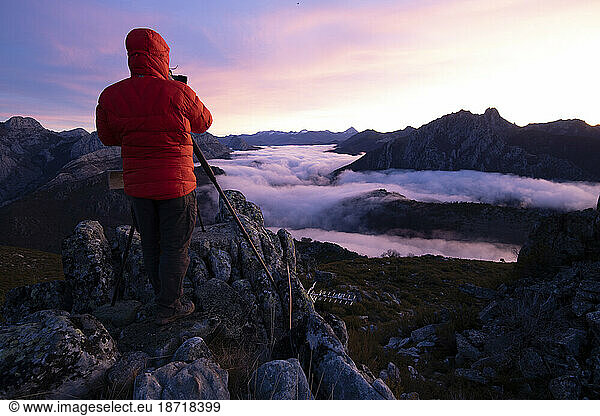 Man Photographing mists at sunrise from the top of some mountains