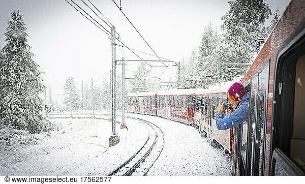 Man photographing the snow falling over mountains during a trip on board of Gornergrat Bahn train  Zermatt  Valais  Switzerland  Europe