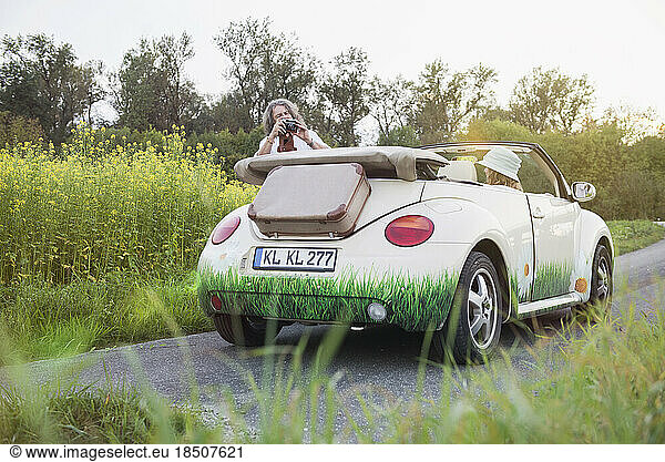 Man photographing woman in a car Beetle Cabrio  Bavaria  Germany