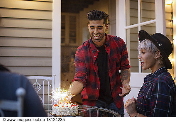 Man placing cake on table for surprised woman