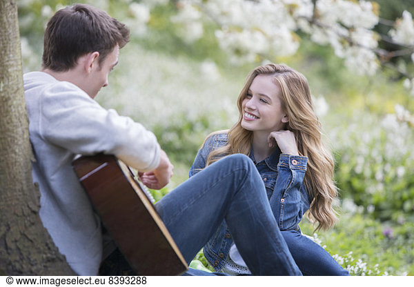 Man playing guitar for girlfriend outdoors