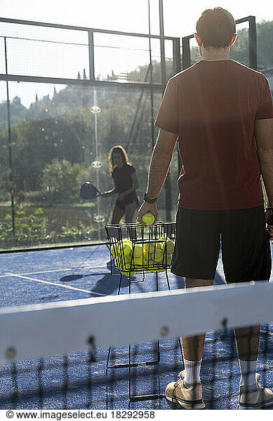 Man playing paddle tennis with woman on sunny day